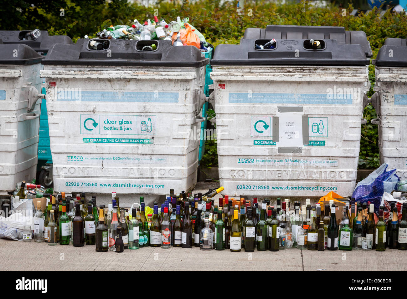 Traboccante di vetro riciclaggio bottle bank in Winchester, Regno Unito con file di bottiglie di vino allineate di fronte Foto Stock