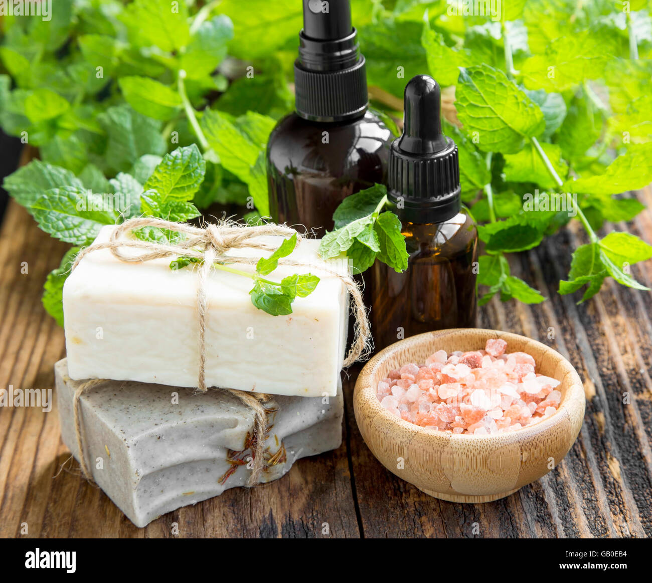 Menta naturale olio spa, sapone naturale, bagno di sale e piante di menta su sfondo di legno Foto Stock