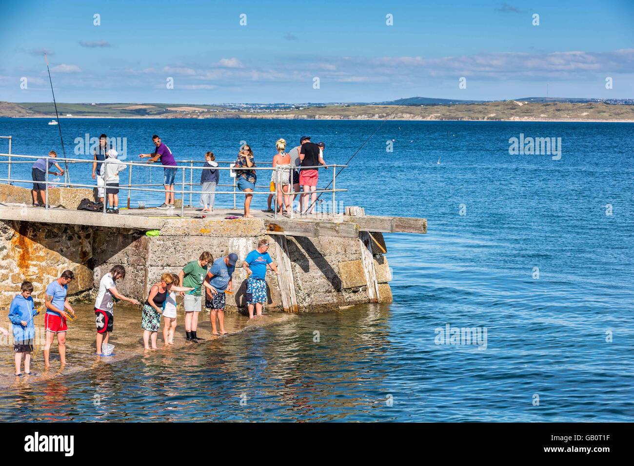 Un gruppo di vacanzieri di pesca con nido per i granchi fuori dalla parete del porto di St. Ives, Cornwall, Regno Unito Foto Stock
