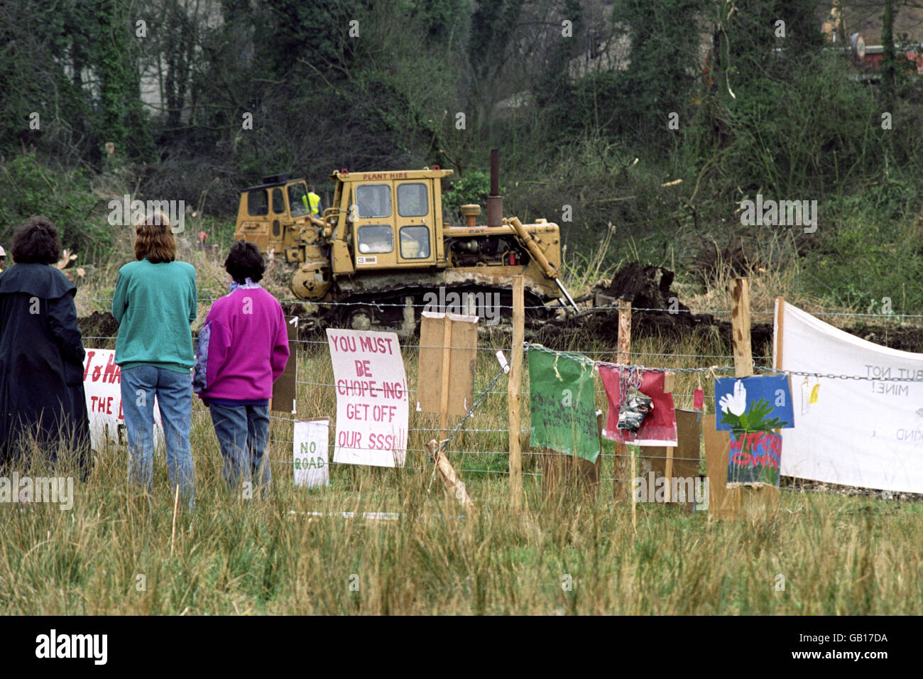 I manifestanti di Friends of the Earth guardano i bulldozer che si spostano sui prati d'acqua di Twyford giù nell'Hampshire mentre preparano la strada per l'estensione dell'autostrada M3. Foto Stock