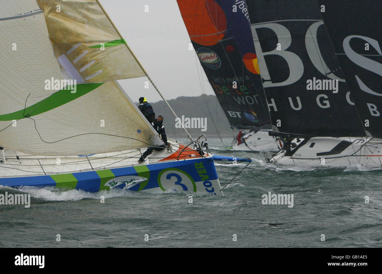 L'equipaggio a bordo dell'eCover di Mike Golding cambia vele (a sinistra) mentre la flotta di yacht Open 60 ad alta tecnologia si avvicina agli aghi durante l'Artemis Challenge intorno alla corsa dell'isola a Skandia Cowes Week. Stavano competendo per vincere 10,000 per dare alla loro carità scelta. Le celebrità che corrono a bordo degli yacht includevano la presentatrice del Big Brother Davina McCall, l'ex decatleta olimpico Dean Macey, il presentatore televisivo Johnny Ball, il rugby inglese James Haskell e Alastair Campbell. Foto Stock