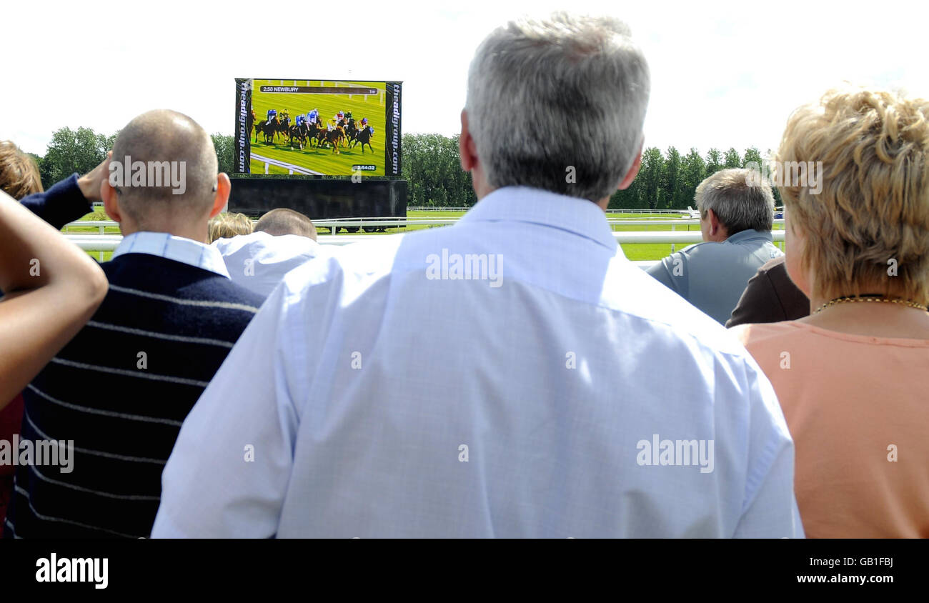 Corse di cavalli - Weatherbys Super Sprint Day - Ippodromo di Newbury. I Racegoers guardano le corse sul grande schermo all'ippodromo di Newbury. Foto Stock
