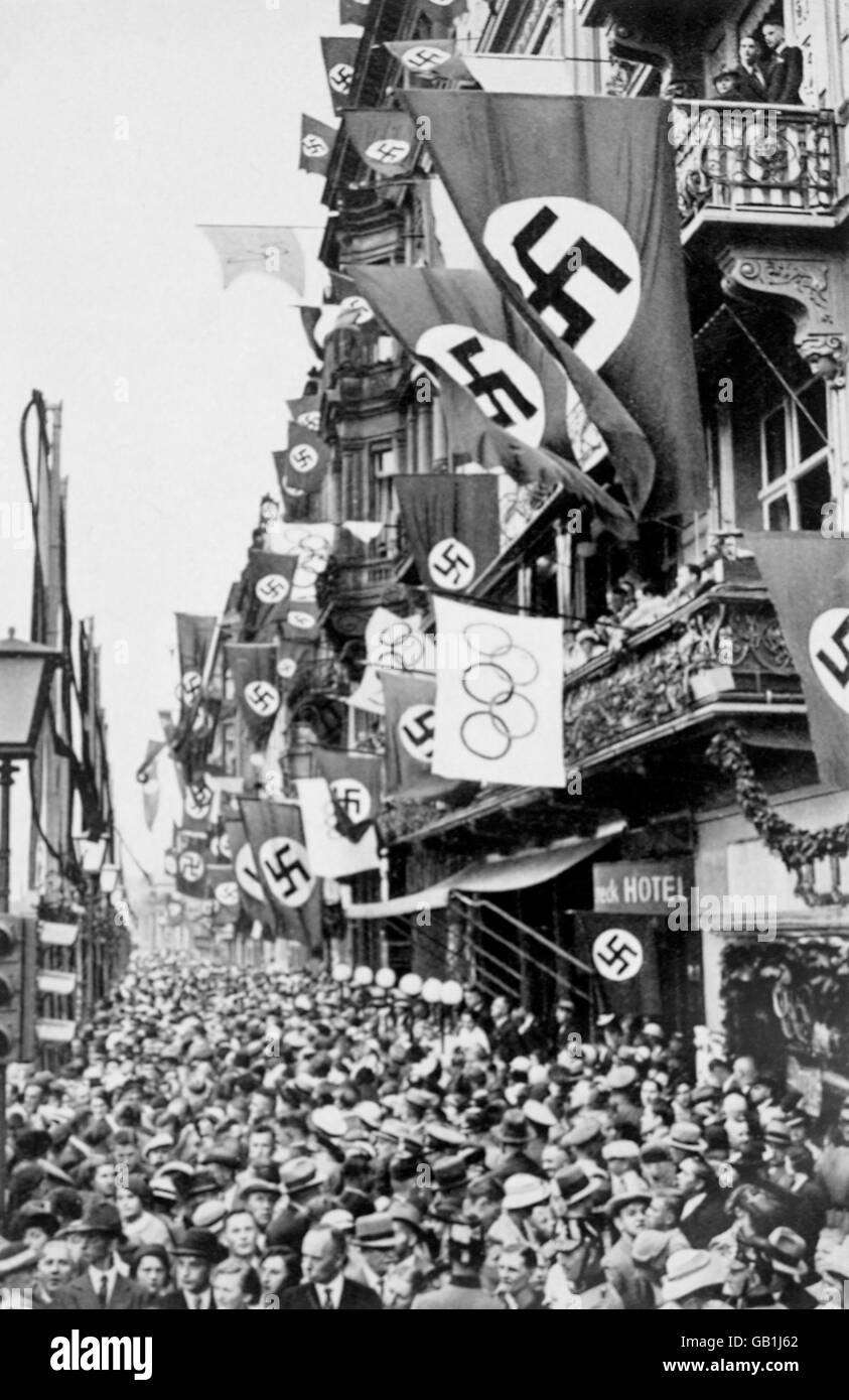 Le strade di Berlino sono costeggiate da folle enormi, che sono festeggiate da bandiere olimpiche e tedesche Foto Stock