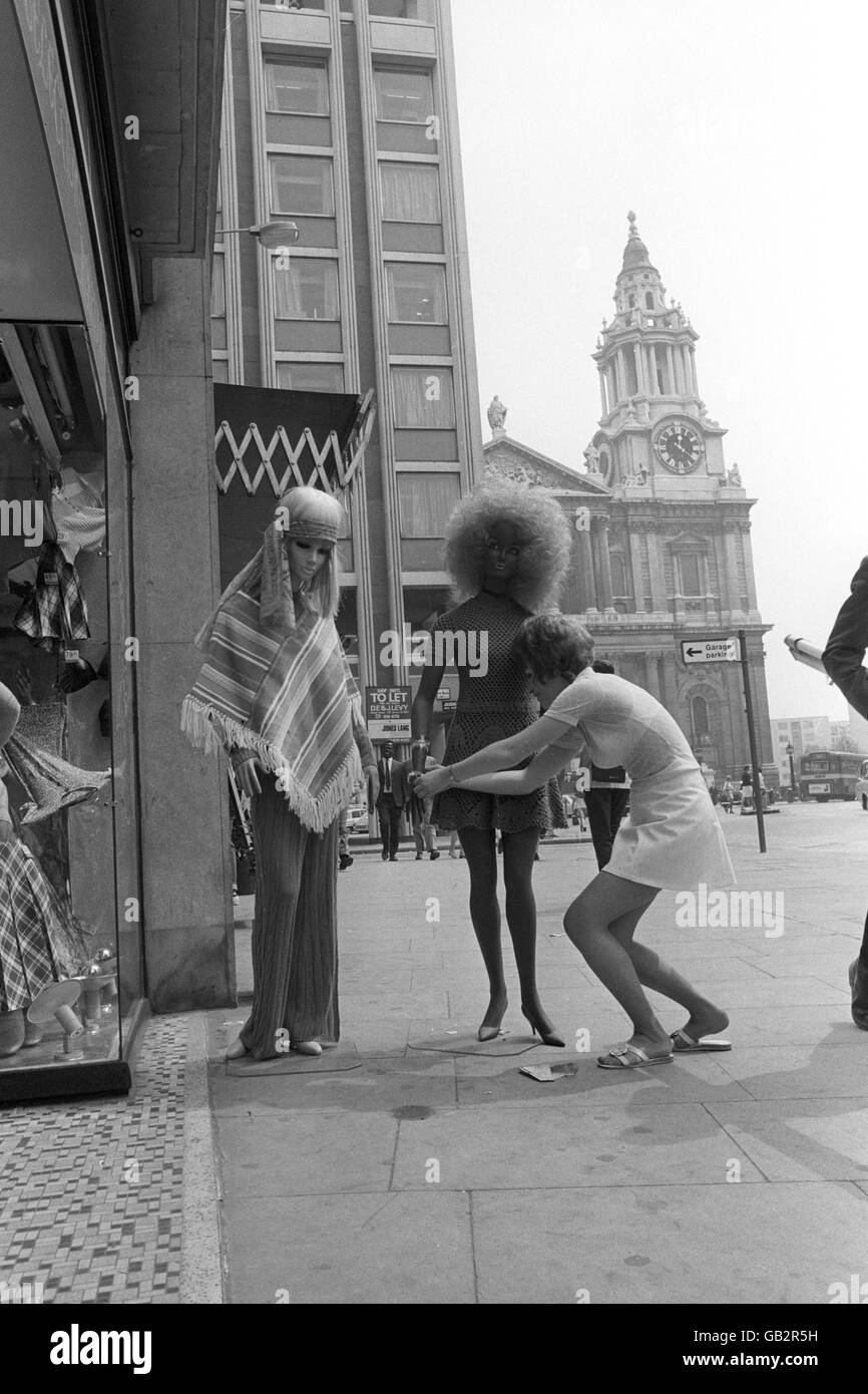 I tentacoli del centro moda di Londra - Carnaby Street - hanno raggiunto la City di Londra. Qui, all'ombra della cattedrale di St. Paul, Miss Gloria Ingram, indossa manichini fuori da una nuova boutique di abbigliamento, attirando ora lavoratori della città oscillanti sulla collina di Ludgate Foto Stock