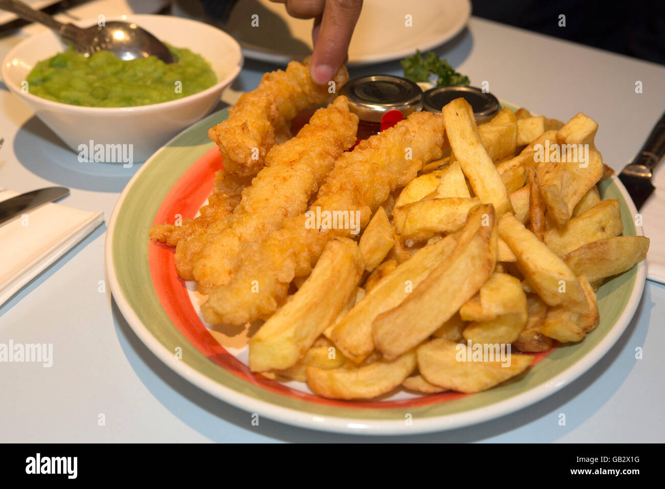 Un diner preleva un chip al Poppies pesce e Chip shop a Londra, Inghilterra. Foto Stock