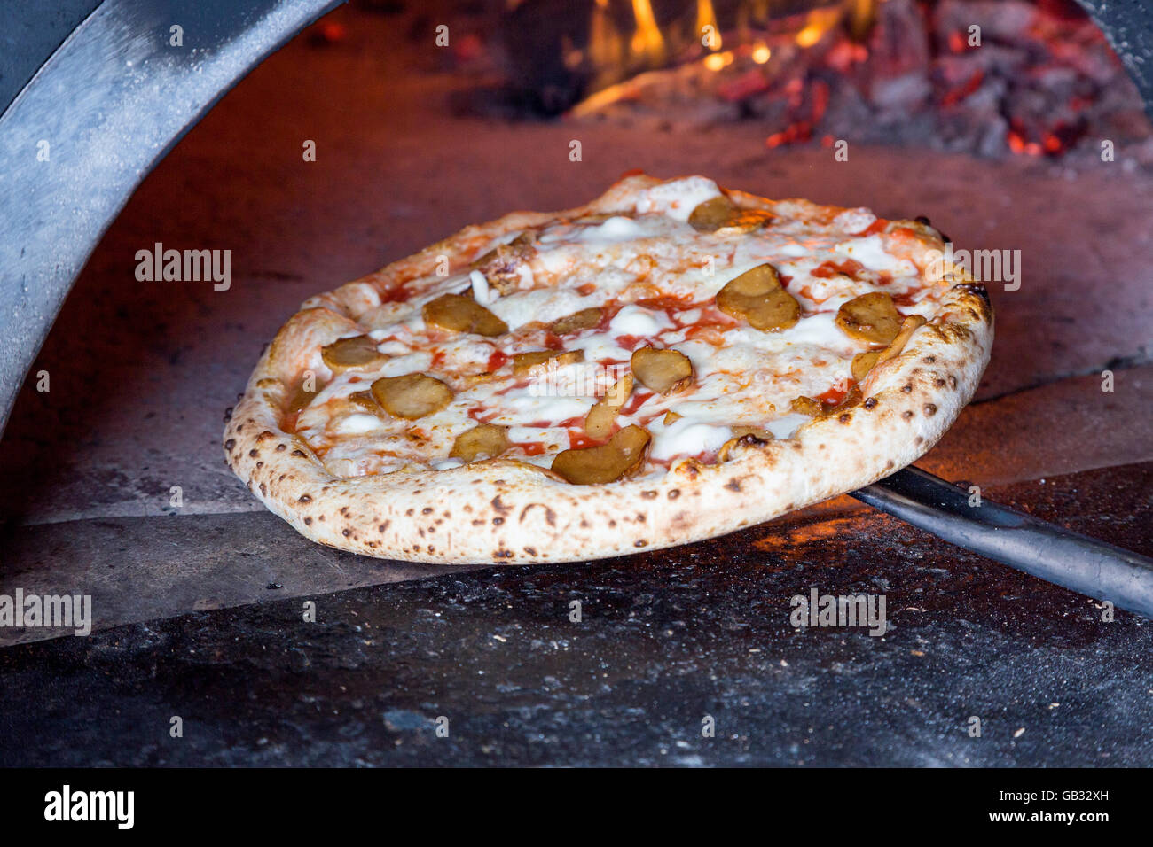 Massive forno per pizza a legna con pizza sulla pala Foto Stock