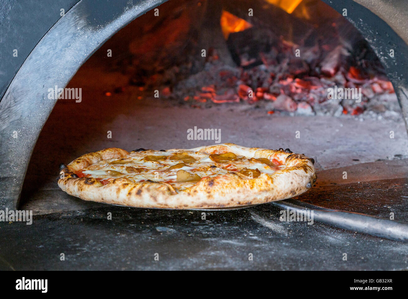 Massive forno per pizza a legna con pizza sulla pala Foto Stock