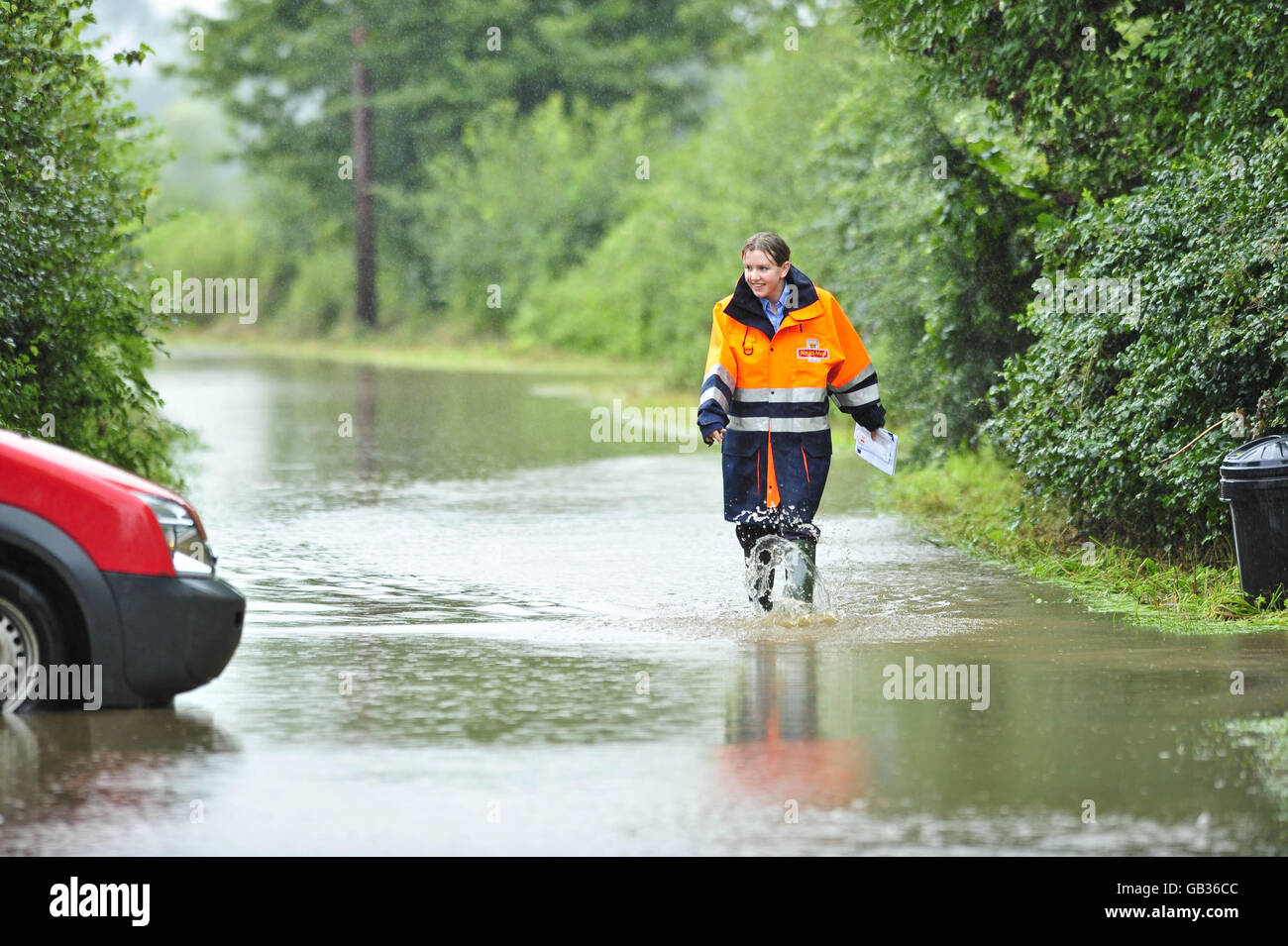 La postdonna della posta reale Elizabeth Brain, 23, che è basato al deposito di Cinderford della posta reale, trasporta la posta nei suoi caricamenti di wellington attraverso l'acqua di inondazione su Rodney Sands in Gloucestershire vicino al fiume Severn. È un'area che alluvia regolarmente e Elizabeth consegna la posta indipendentemente dal tempo, anche se in questa occasione la strada era stata allagata così male che non poteva passare per consegnare ad alcune case più in basso la corsia. Foto Stock