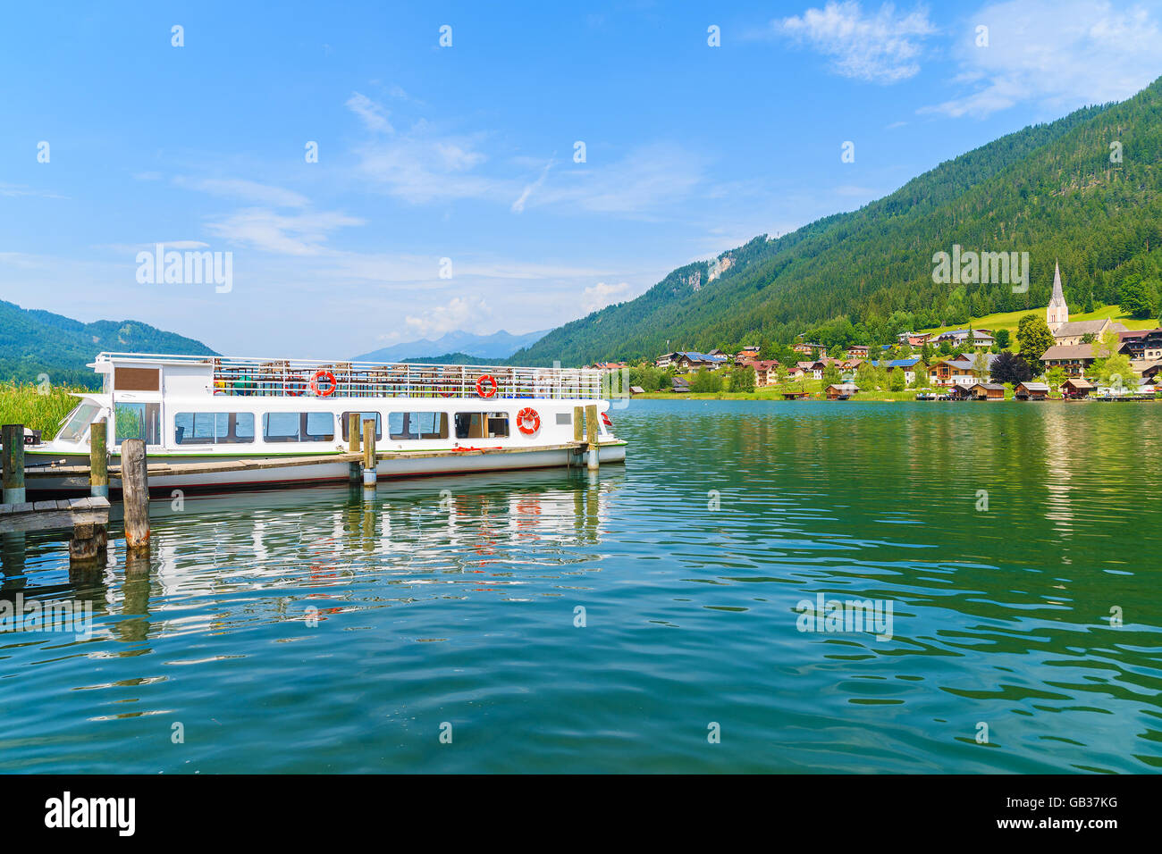 Imbarcazione turistica ancorata su acqua verde lago Weissensee in estate il paesaggio di montagna delle Alpi, Austria Foto Stock