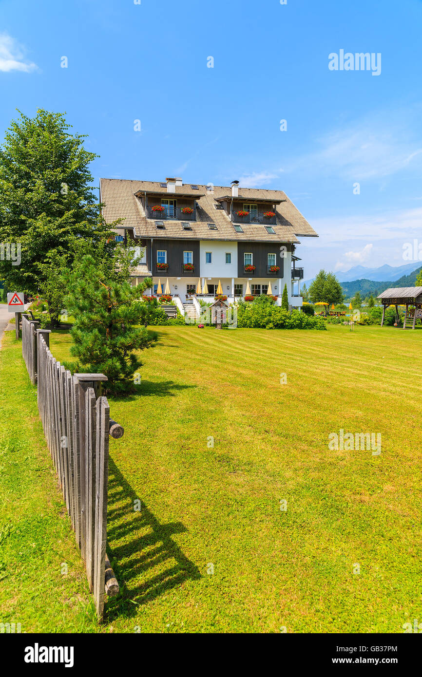 Staccionata in legno sul prato verde e la vista della tipica casa alpina in estate il paesaggio di montagna delle Alpi, il lago Weissensee, Austria Foto Stock
