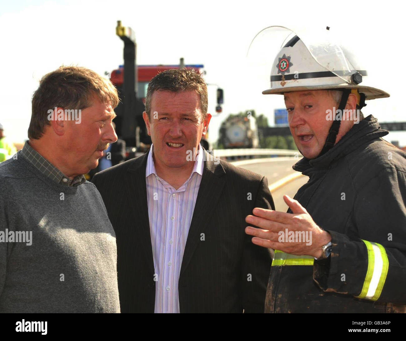 I ministri dell'Irlanda del Nord Sammy Wilson (a sinistra) e Conor Murphy (al centro) parlano con il comandante della stazione dei vigili del fuoco di Belfast Gary Allen al sottopassaggio Westlink allagato a Belfast dopo che le forti piogge hanno causato un'alluvione diffusa. Foto Stock