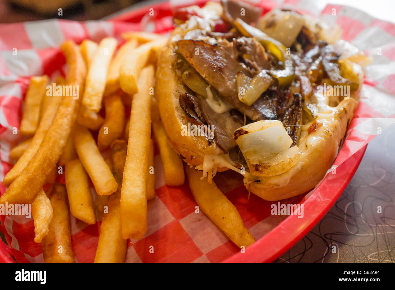 Un confuso Philly Cheesesteak con cipolle e peperoni funghi, patate fritte sul lato Foto Stock