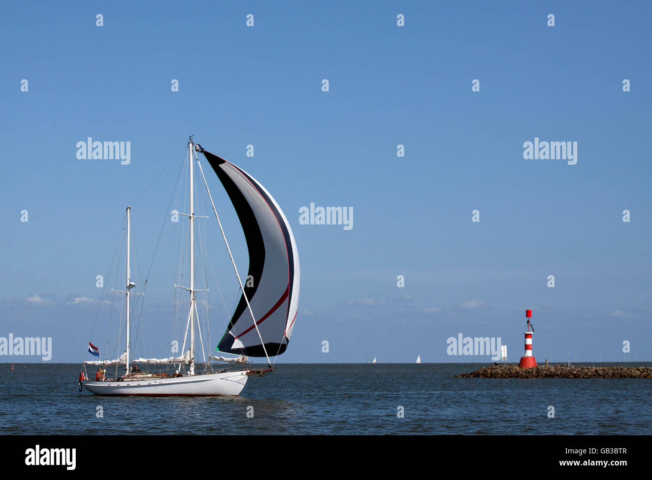 ENKHUIZEN, PAESI BASSI - JUNI 7 ,2015 bianco con barche a vela vela spinnaker vele passato una diga con un faro del porto di Foto Stock