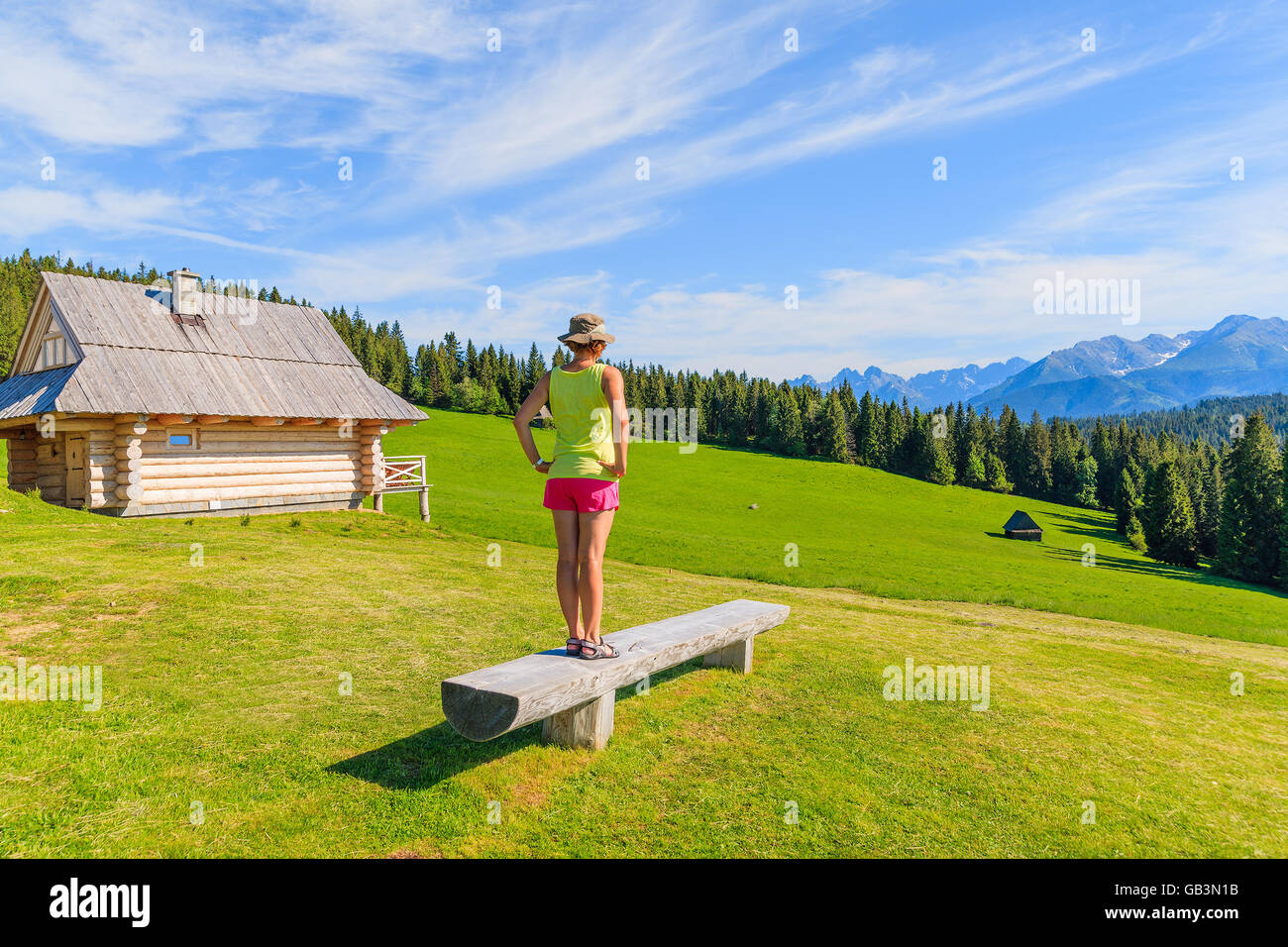 Giovane donna tourist permanente sulla panchina sul prato verde e guardando il Tatra, Polonia Foto Stock