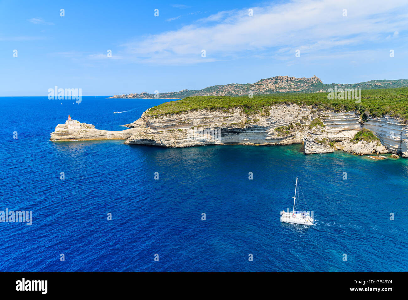 Un bianco catamarano a vela sul mare blu acqua lungo la costa della Corsica, Francia Foto Stock