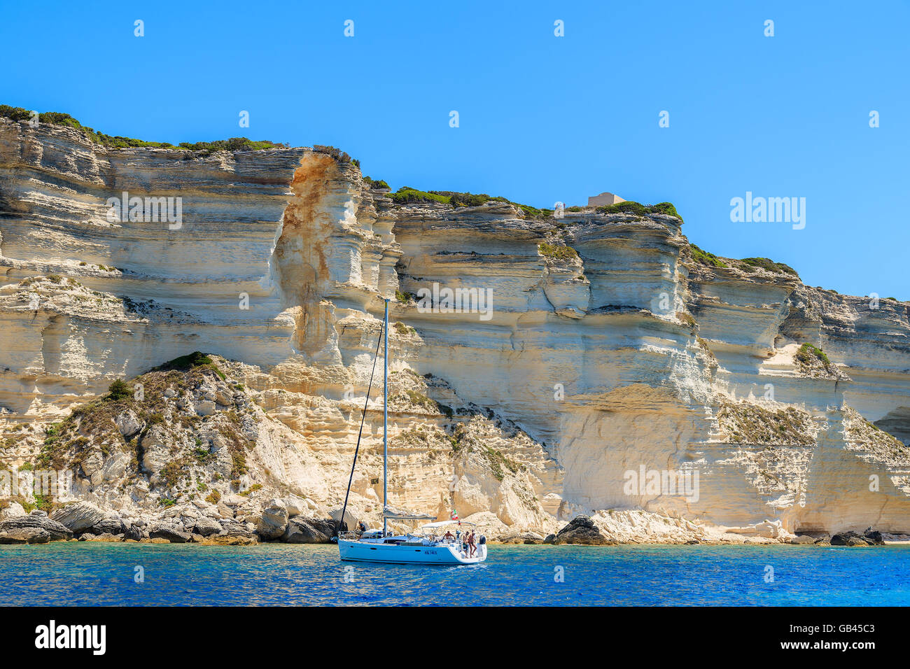 La CORSICA, Francia - giu 25, 2015: barca a vela in crociera sul mare vicino a Bonifacio roccia calcarea rocce. Bonifacio è la maggior parte delle visite Foto Stock