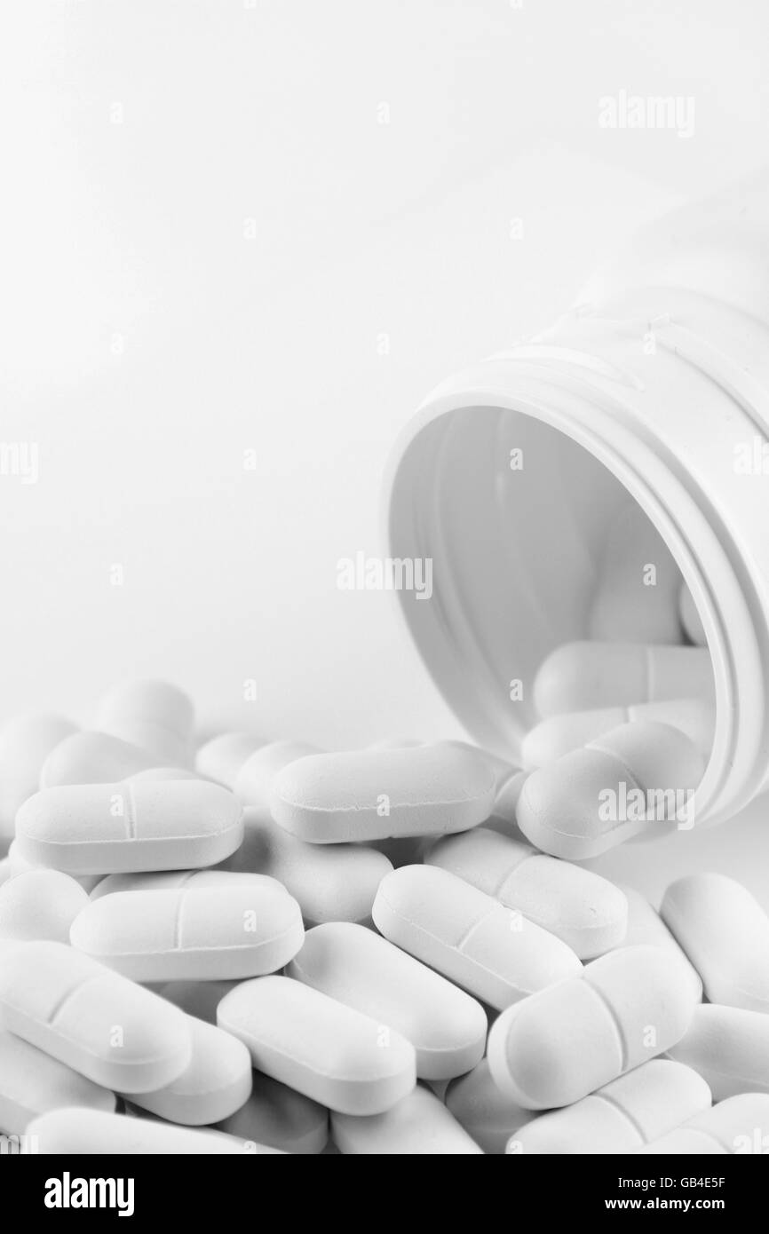 Pills fuoriuscita dal contenitore in plastica Foto Stock