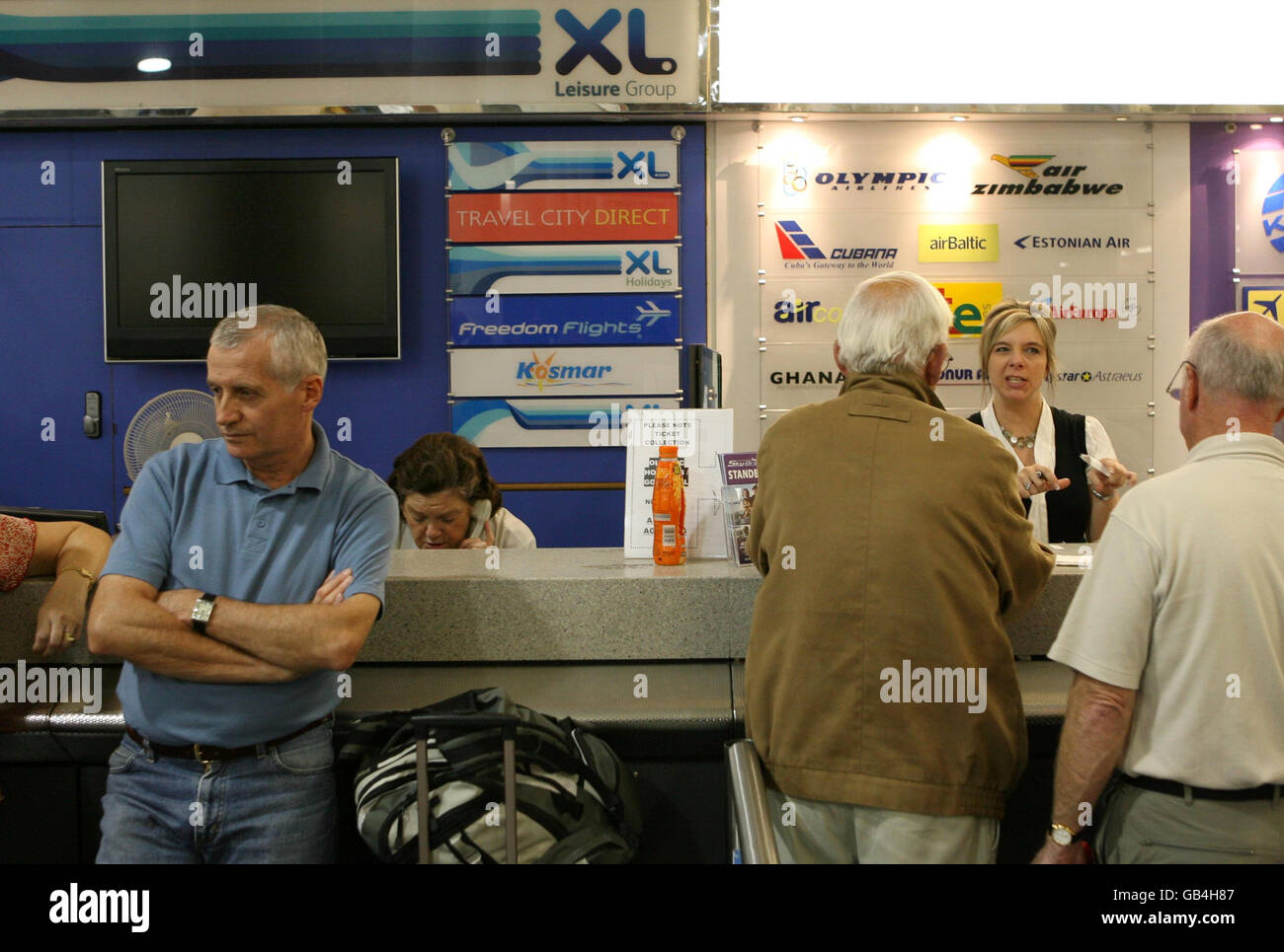I viaggiatori aspettano informazioni all'aeroporto di Gatwick, West Sussex. Foto Stock