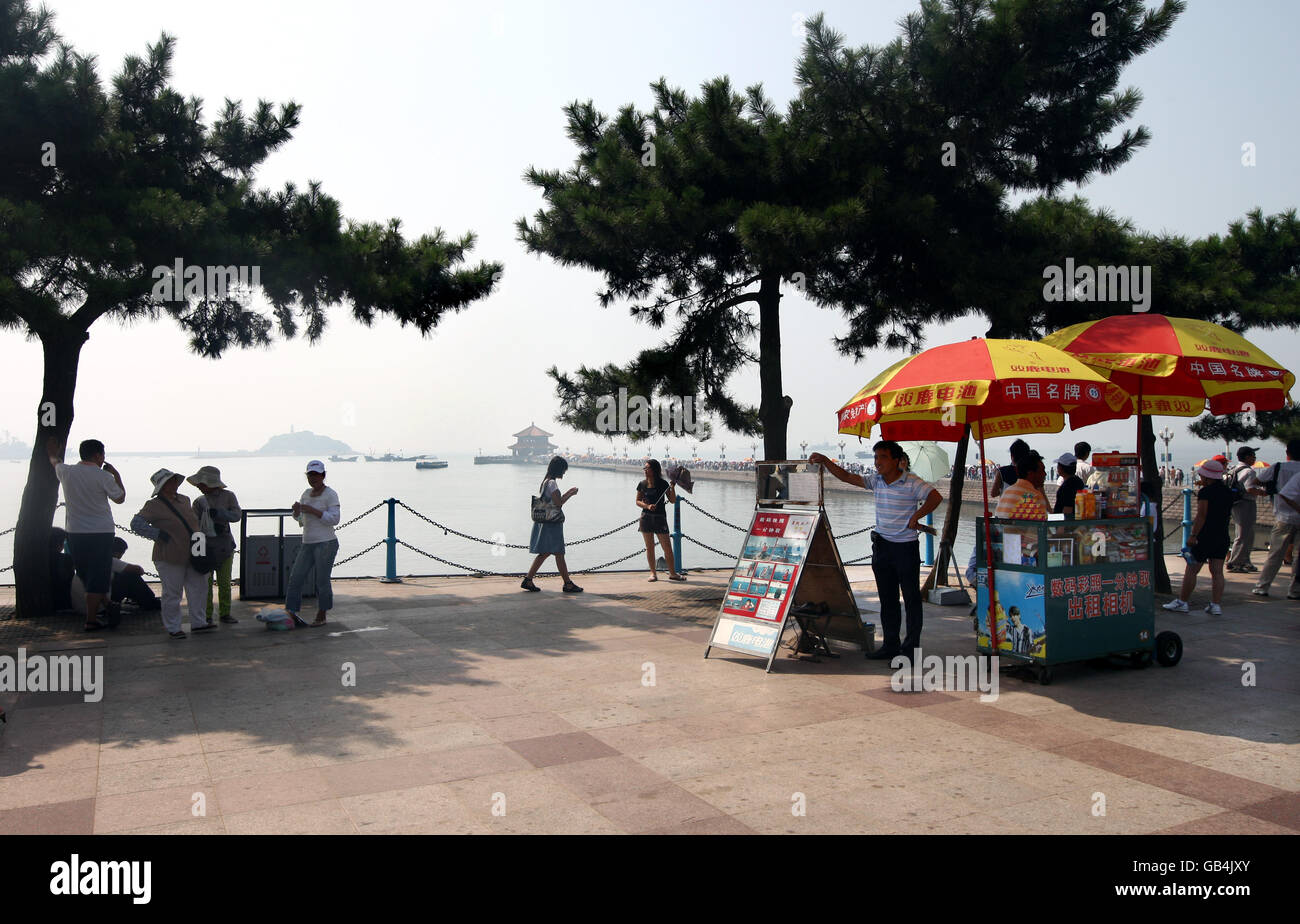 I fotografi di mare con i loro ombrelli rossi e gialli aspettano i costumi sul molo di Zhanqiao, sul lungomare di Qingdao. Foto Stock I fotografi di mare con i loro ombrelli rossi e gialli aspettano i costumi sul molo di Zhanqiao, sul lungomare di Qingdao. Foto Stock