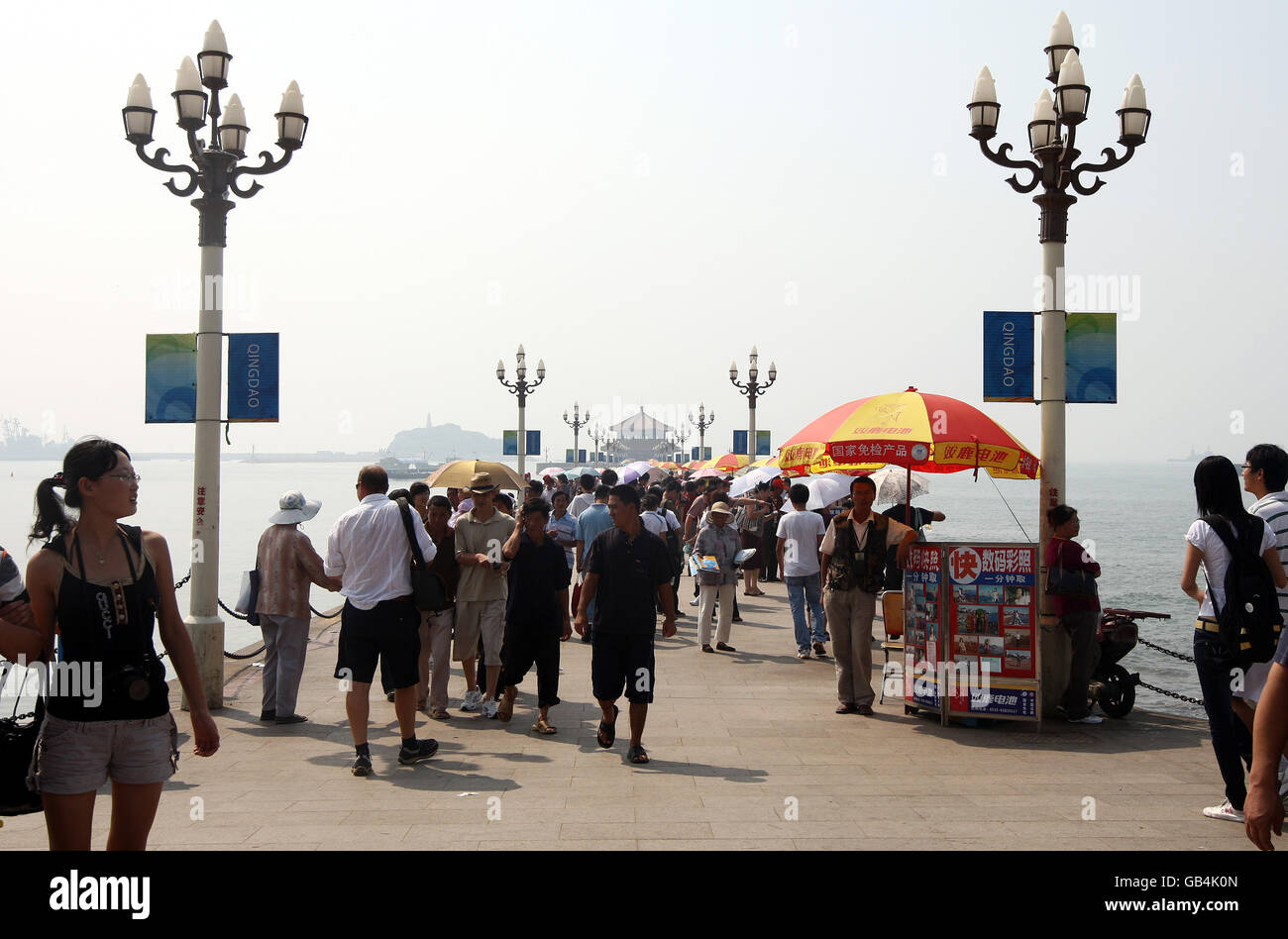 I fotografi di mare con i loro ombrelli rossi e gialli aspettano i costumi sul molo di Zhanqiao, sul lungomare di Qingdao. Foto Stock I fotografi di mare con i loro ombrelli rossi e gialli aspettano i costumi sul molo di Zhanqiao, sul lungomare di Qingdao. Foto Stock