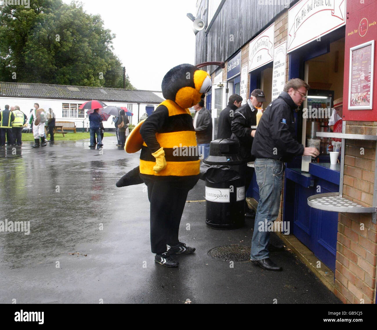 Il signor Bumble la mascotte per il Barnet FC si accoda per un hamburger dopo la decima Mascot Grand National all'Huntingdon Racecourse, Brampton, Huntingdon, Cambridgeshire. Foto Stock