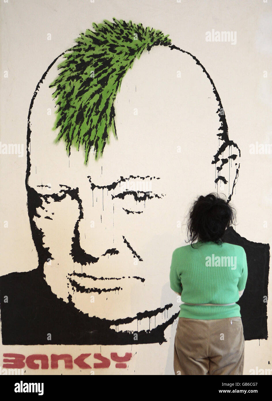 Un visitatore di Bonhams cammina accanto a un dipinto Banksy chiamato Turf War, che si prevede di sollevare tra il 50,000 e il 80,000 quando è all'asta il 23 ottobre in aiuto della carità Surfers contro Sewage, a New Bond Street, Londra. Foto Stock