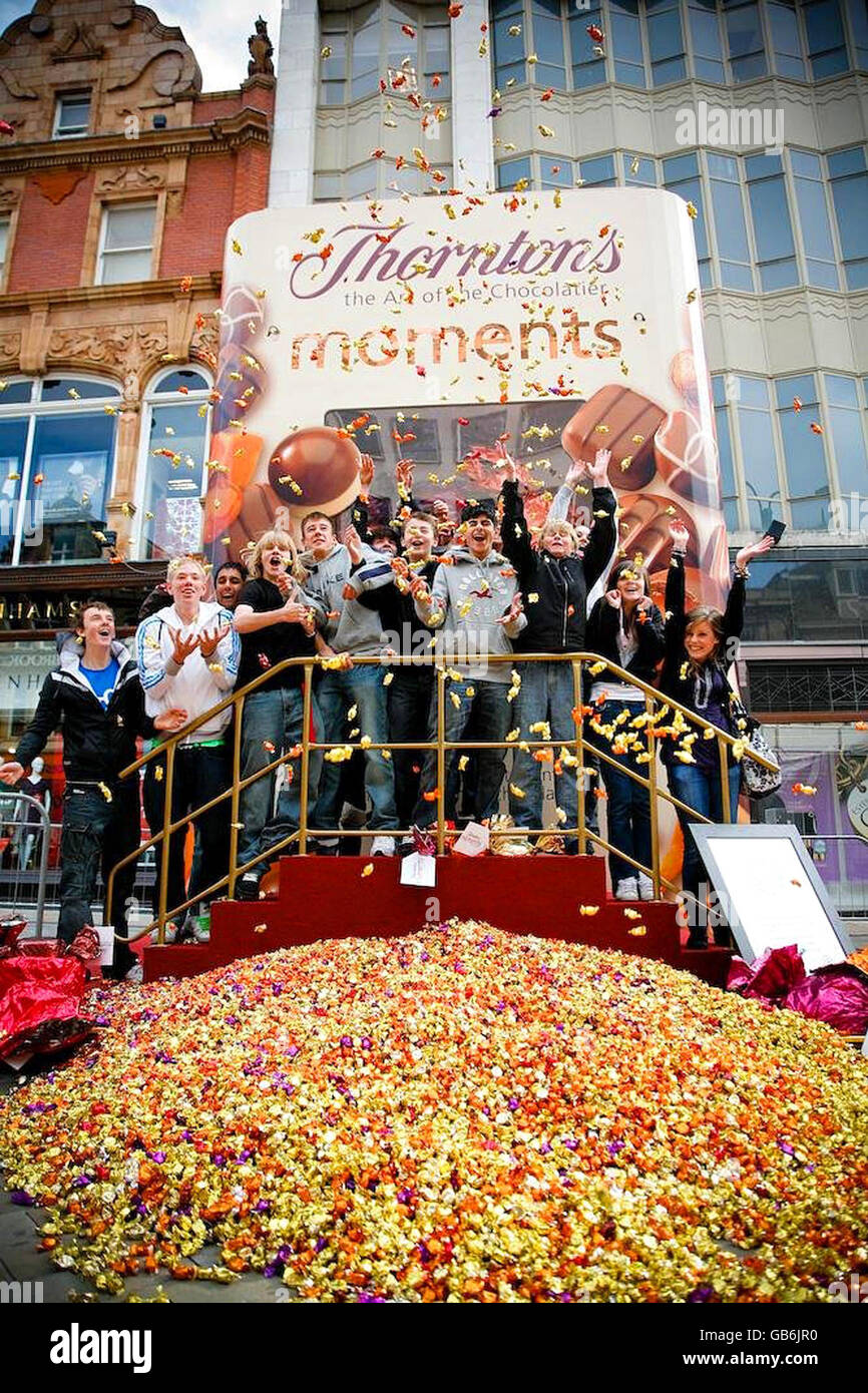 Gli amanti dello shopping festeggiano per assaggiare alcuni dei 250,000 dolci della scatola di cioccolatini più grande del mondo, fuori da un negozio Thorntons di Leeds. Foto Stock