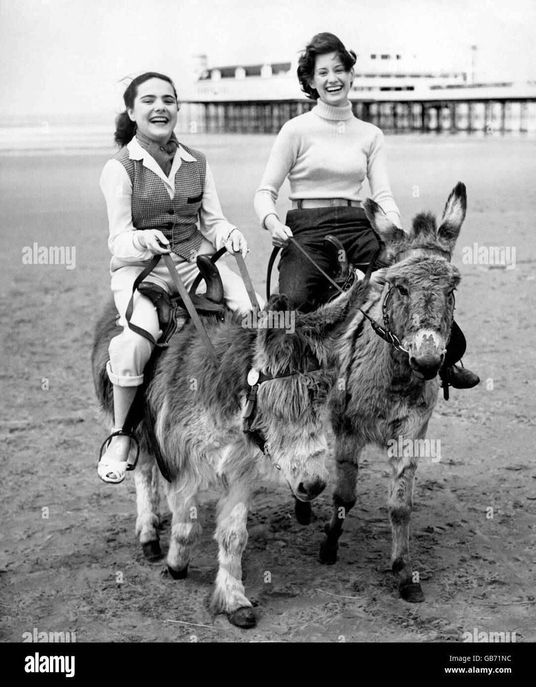 Giugno Beckett (a sinistra) e Shirley Boyer godere di un giro sugli asini sulla spiaggia a Weston-Super-Mare. Foto Stock