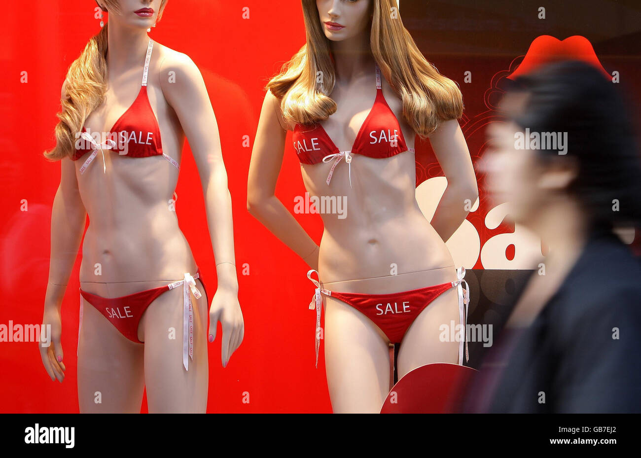 Un acquirente passa accanto ai cartelli di vendita nella finestra di Ann Summers, Oxford Street, nel centro di Londra. Foto Stock