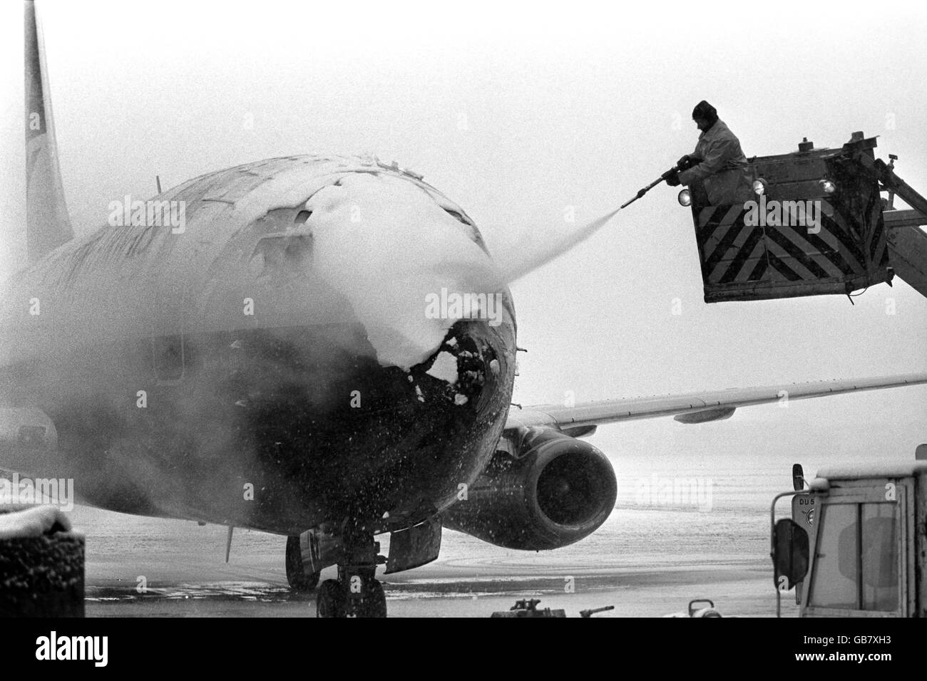 Un dipendente dell'aeroporto di Heathrow disciem un aereo sulla pista coperta di neve. Foto Stock