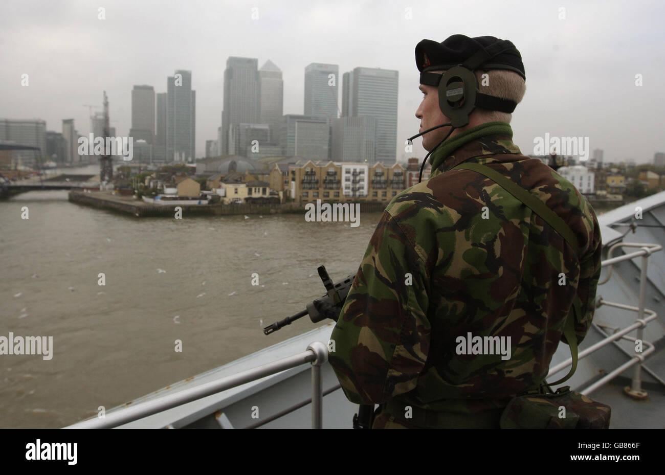 Un marinaio della Royal Navy si trova sul ponte della portaerei HMS Illustrious mentre gira di fronte a Canary Wharf prima di ormeggiare a Greenwich, all'inizio di una visita di nove giorni a Londra. Foto Stock