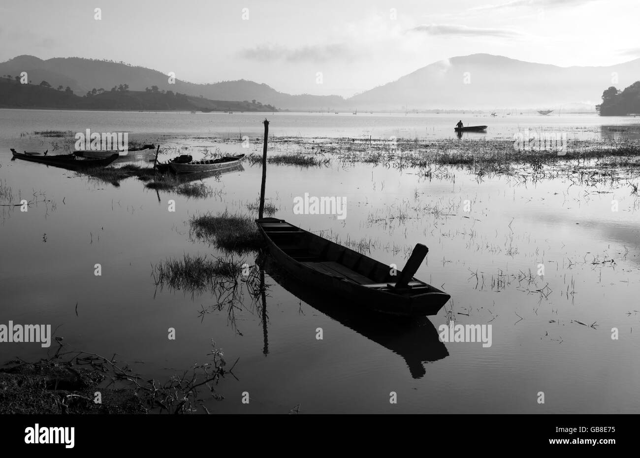 Il Vietnam tranquillo lago di prima mattina con Black & White tono, pescatori fanno vivere di vi, barca riflettere sulle acque di superficie Foto Stock