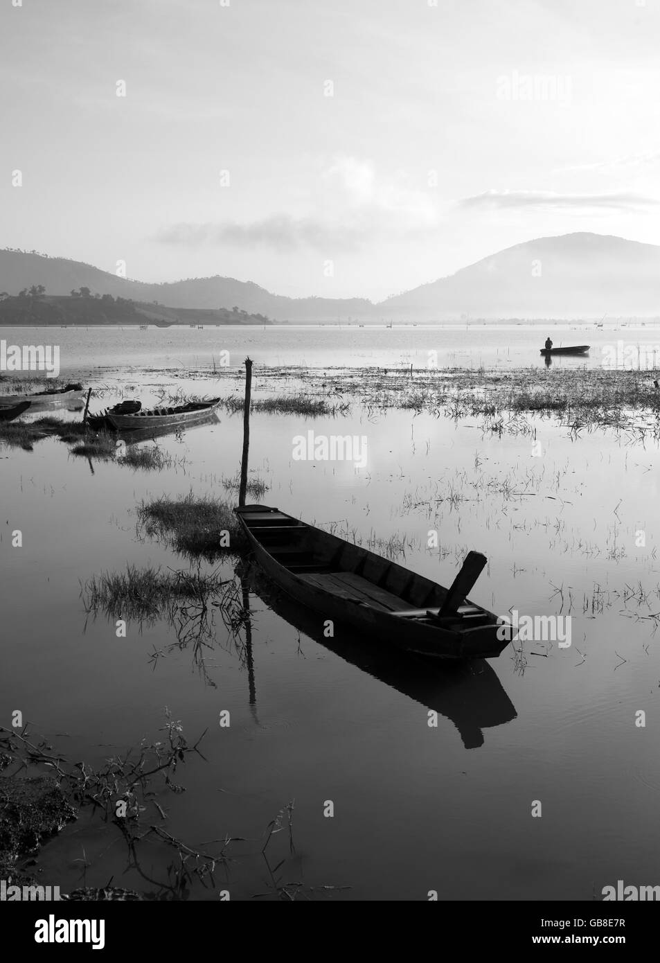 Il Vietnam tranquillo lago di prima mattina con Black & White tono, pescatori fanno vivere di vi, barca riflettere sulle acque di superficie Foto Stock