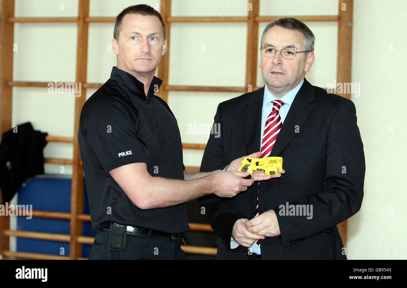 L'assessore Alan Campbell, a destra, viene mostrato un fucile da taser da un ufficiale durante una fotocellula presso i quartier generale della polizia a Ponteland. Foto Stock