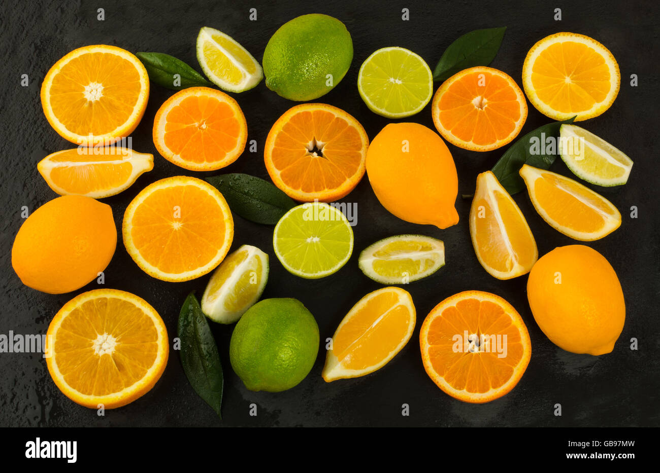 Lime, limone, arancio e mandarino su sfondo nero. Il cibo fresco. Frutti maturi. Gli agrumi. Cibo vegetariano. Frutta Mista. Freschi Foto Stock