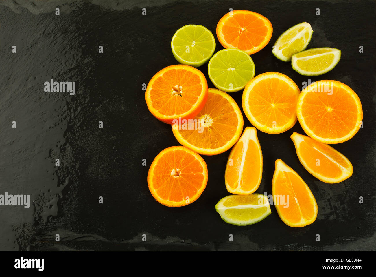 Limes, arance e limoni su sfondo nero, copia dello spazio. Il cibo fresco. Frutti maturi. Gli agrumi. Cibo vegetariano. Frutta fresca. Foto Stock
