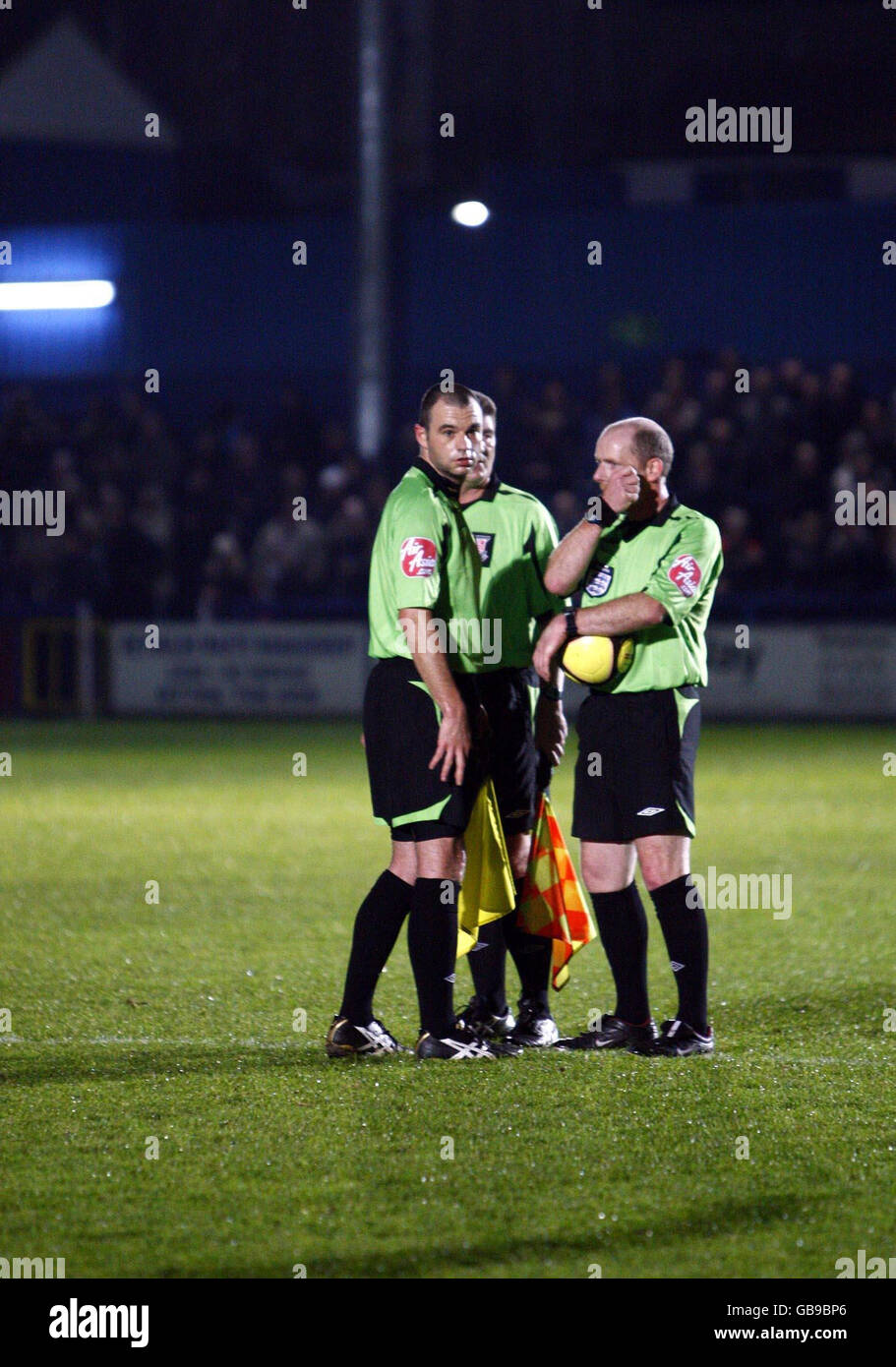 L'arbitro David Phillips (a sinistra) si consulta con i suoi due uomini di linea durante la prima partita di gioco della fa Cup a New Recreation Road, Essex. Foto Stock