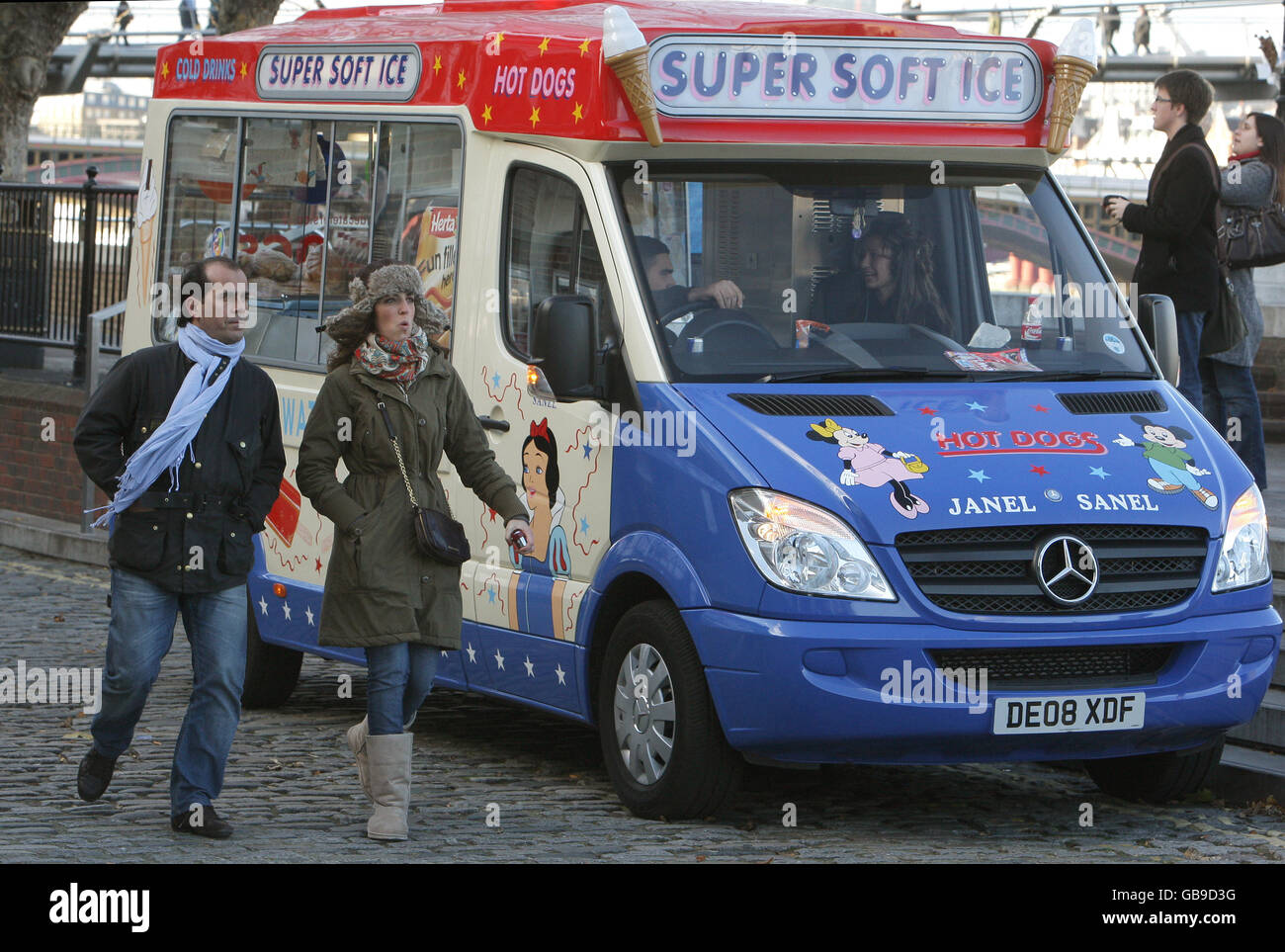 Due pedoni passano davanti a un gelateria sulla South Bank, Londra, mentre un fronte meteo artico colpisce il Regno Unito. Foto Stock