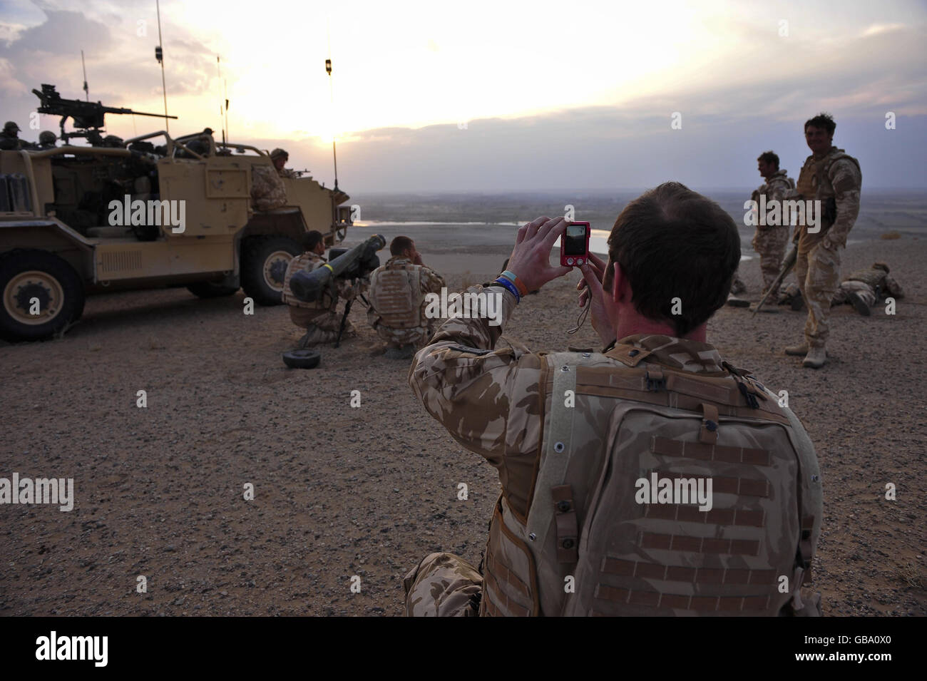 Capitano Charles Robinson dal 1 ° le Guardie del Dragoon Queens scatta una foto nel sole di tramonto delle sue truppe, mentre osservano e tentano di aiutare a localizzare le forze nemiche in una lotta contro il fuoco tra i talebani e l'esercito nazionale afghano nella regione di Nawar della provincia di Helmand, Afghanistan. Foto Stock
