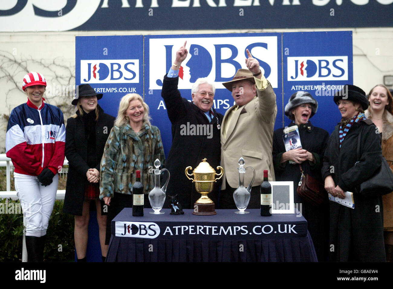 La presentazione per i vincitori del re Pertemps George Vi Steeple Chase con il proprietario Jim Lewis (l) AS Celebra la vittoria del suo cavallo Edredon Bleu Foto Stock