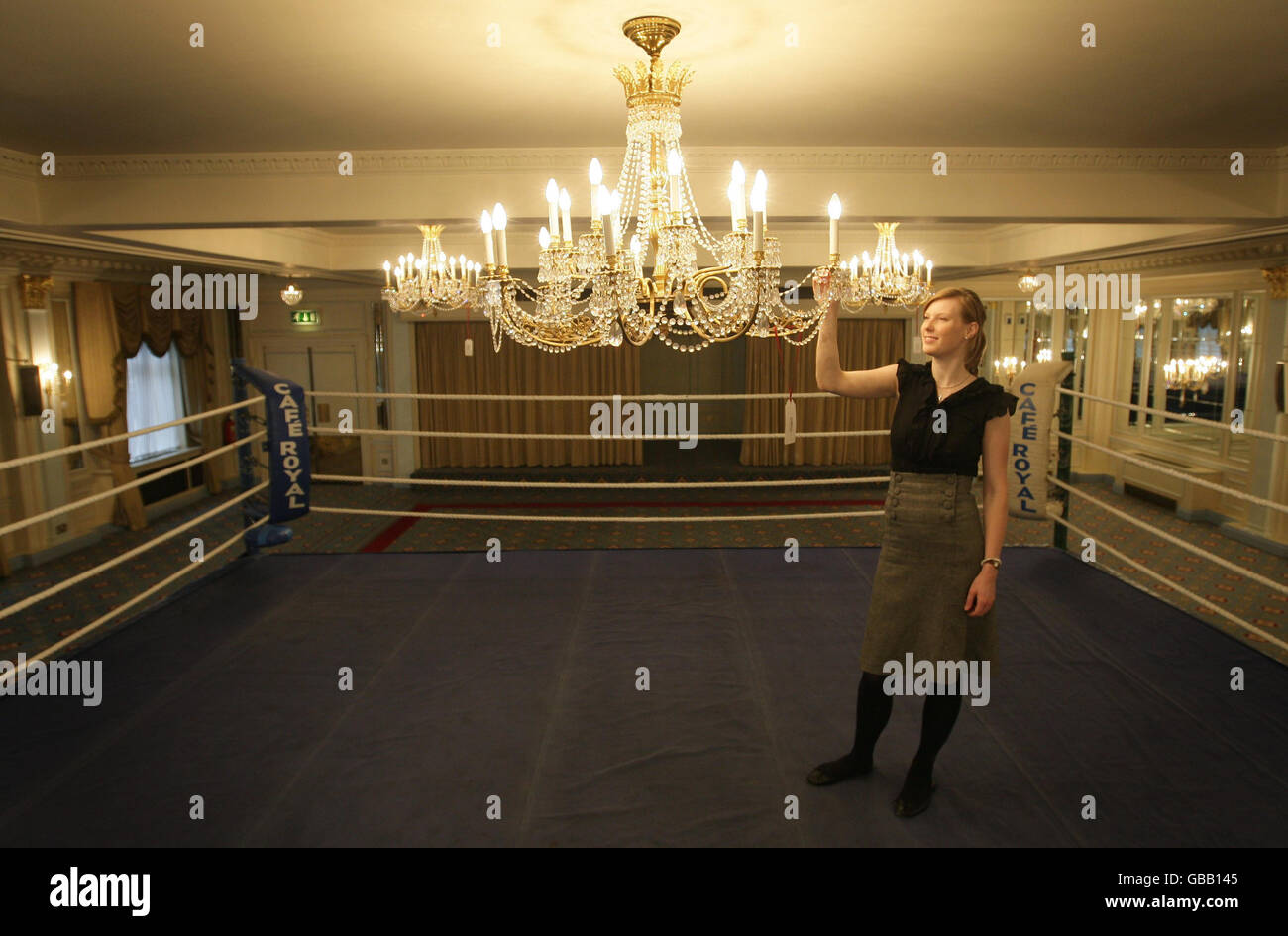 Un membro dello staff di Bonhams esamina un lampadario sopra l'originale anello di boxe del caffè, che è stato utilizzato in molti degli eventi di boxe black tie che il Cafe Royal ha ospitato nel corso degli anni, come parte della chiusura dell'asta al Cafe Royal, Piccadilly, Londra. Foto Stock