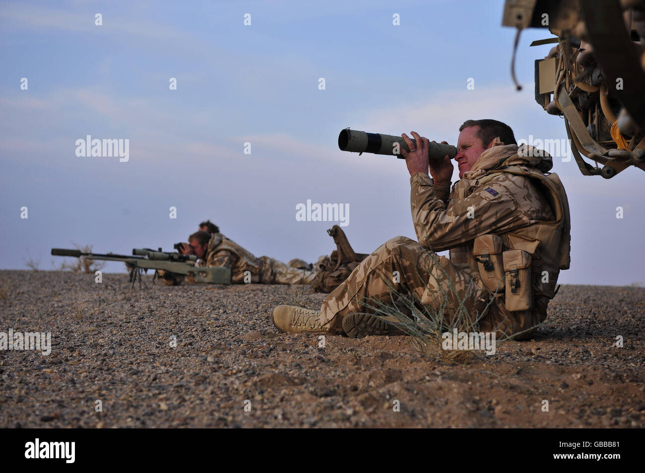 Il primo il Queens Dragoon Guards 'A' Squadron Comandante maggiore Charles Langley-Waggett utilizza un telescopio per individuare l'attività nemica da La cima di una cresta nel deserto orientale che si affaccia sulla regione di Nawa della provincia di Helmand dove un incendio Scoppiò la lotta tra i talebani e l'esercito nazionale afghano Foto Stock