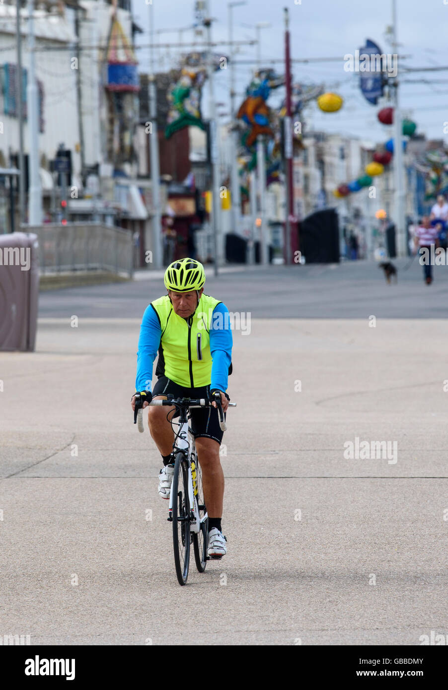 Uomo giubbotto luminoso e ciclismo casco, in sella alla sua moto lungo la Promenade di Blackpool, Lancashire, Regno Unito Foto Stock