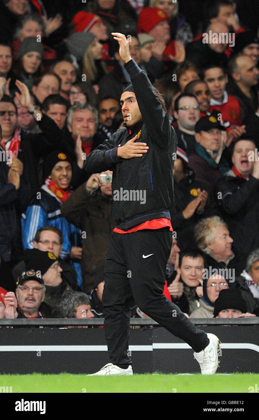 Carlos Tevez di Manchester United fa gesti ai tifosi mentre si riscalda sulla linea di contatto toccando il badge del club il suo top di allenamento Foto Stock