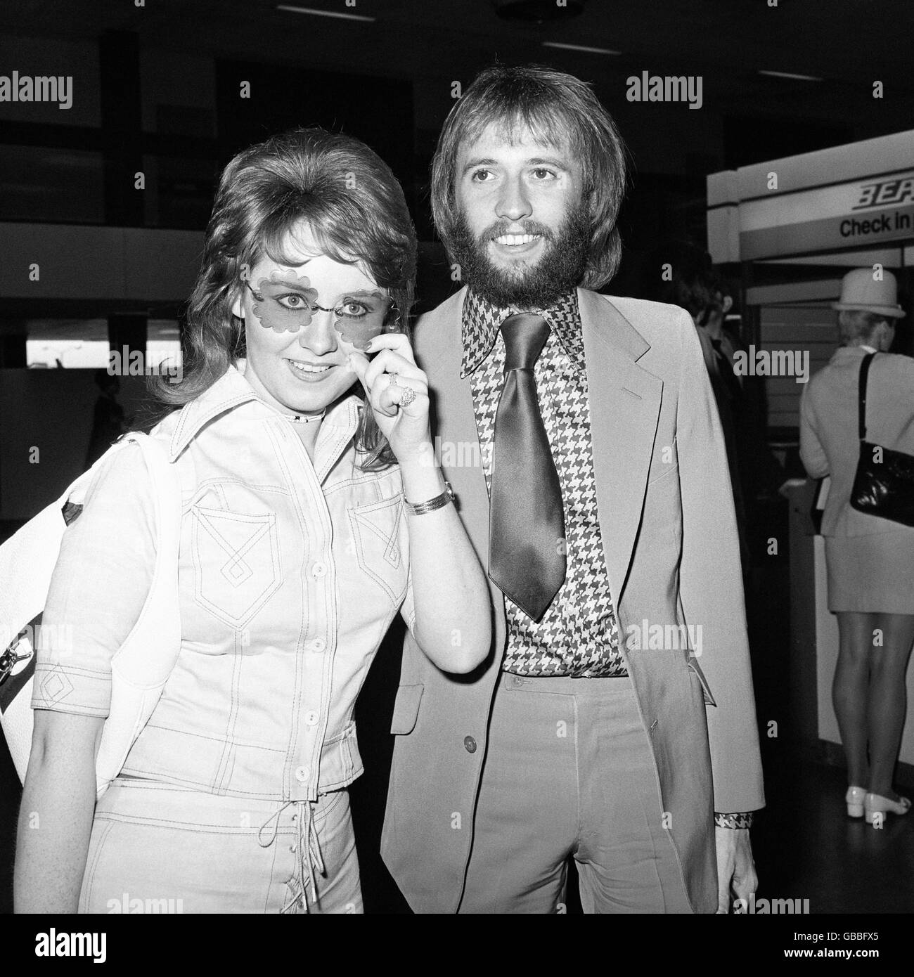 Cantante pop Lulu con suo marito Maurice Gibb all'aeroporto di Heathrow. Lulu indossava jeans blu e sfumature a forma di sole. Foto Stock