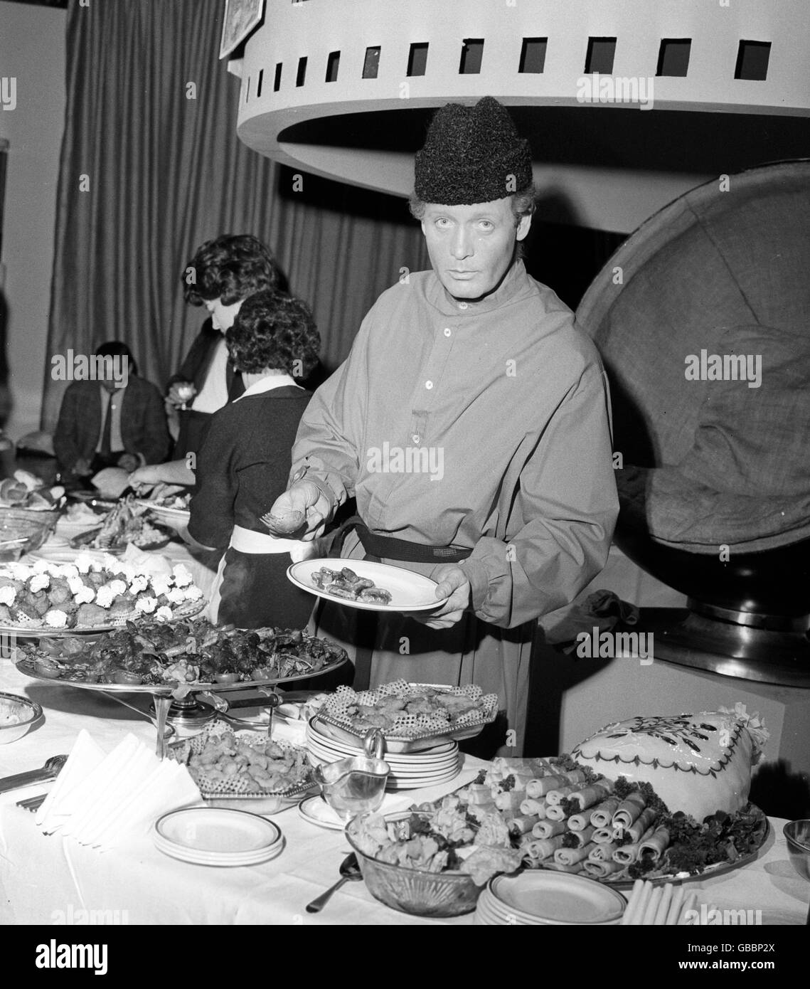 Patrick McGoohan, la star della nuova grande serie di film autunnali di ATV, 'The Prisoner', serve cibo in costume in stile serf, alla stampa su un palco sonoro presso gli MGM Studios, Boreham Wood. Foto Stock