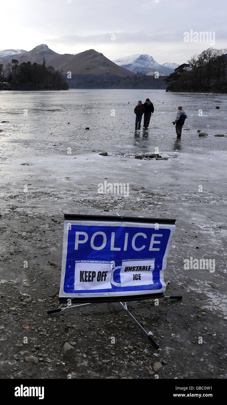Derwentwater vicino Keswick solido congelato con un segno di avvertimento di ghiaccio della polizia oggi come l'incantesimo freddo continua. Foto Stock