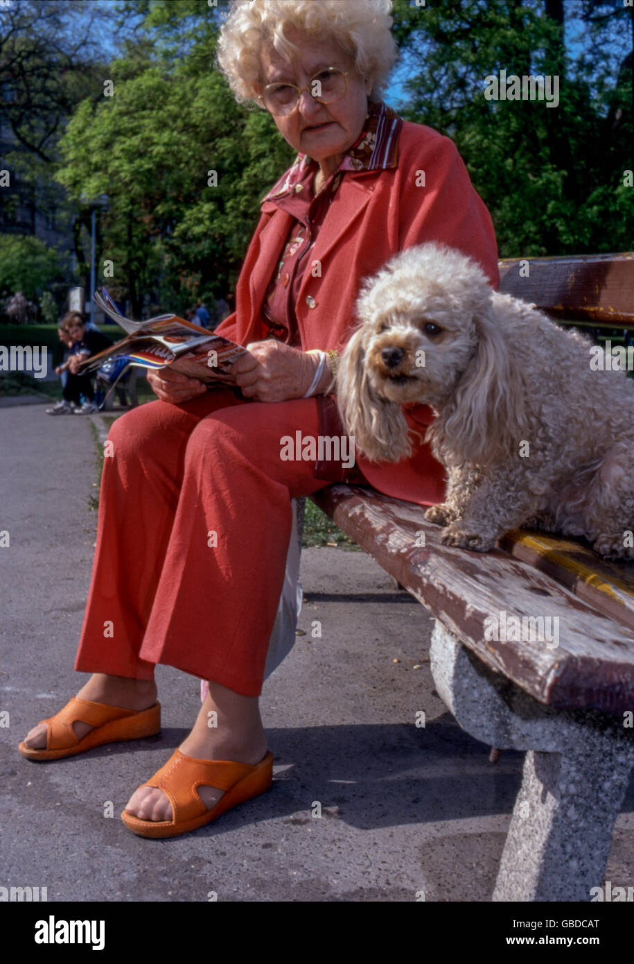 Pensionato anziana donna anziana con il suo cane, una passeggiata nel parco, Praga, Repubblica Ceca stessa panchina Senior 70 Foto Stock