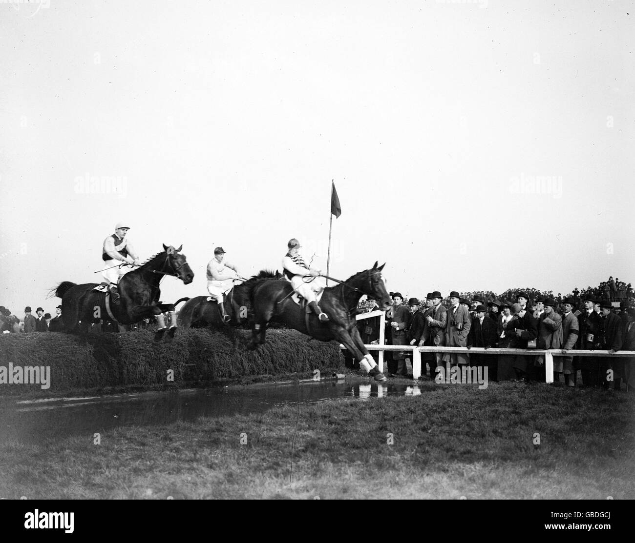 Il salto in acqua durante il Grand National all'Ippodromo di Aintree nel 1914. Foto Stock