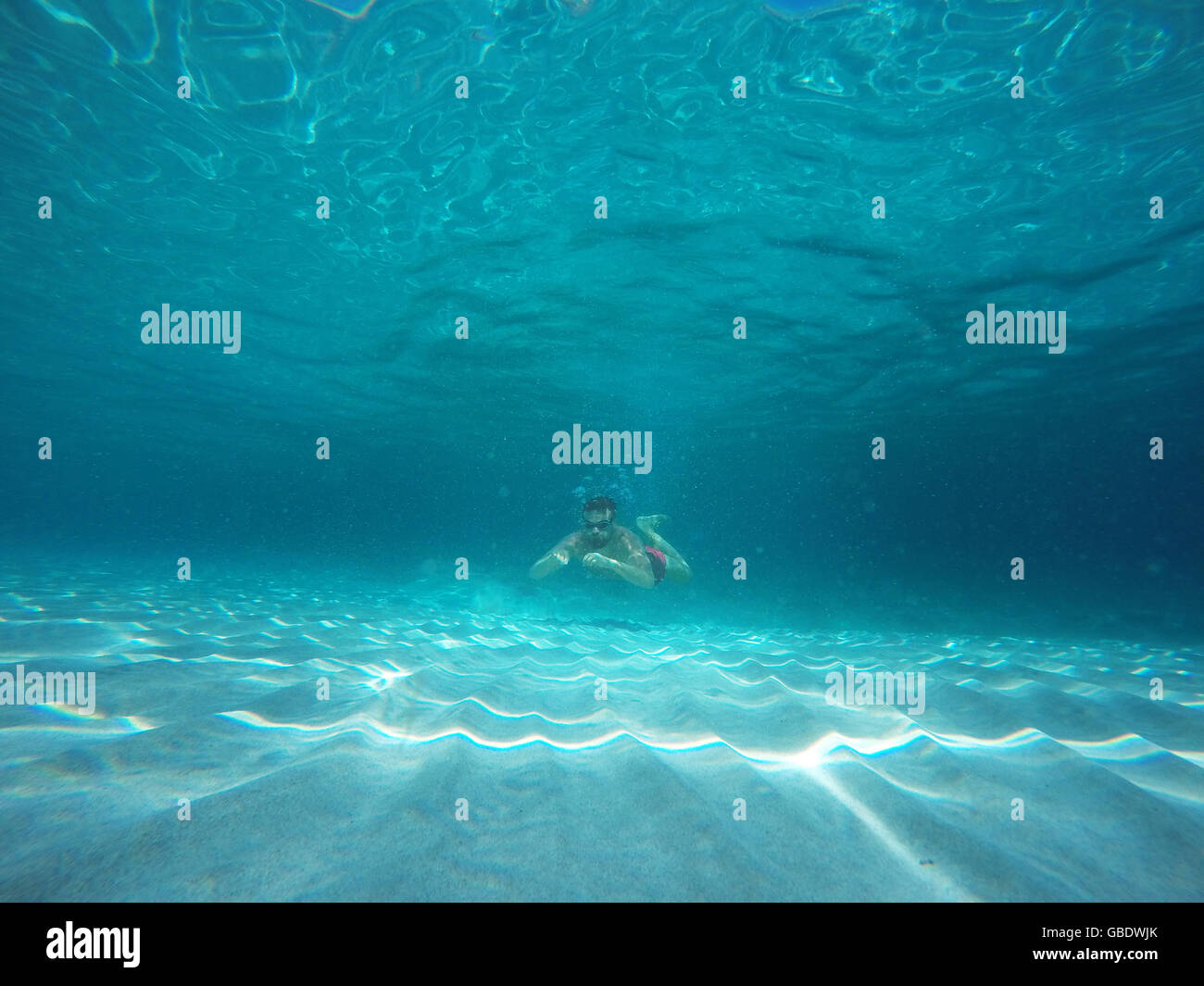 Barba Giovane Uomo con occhiali immersioni in acqua pulita azzurra Foto Stock